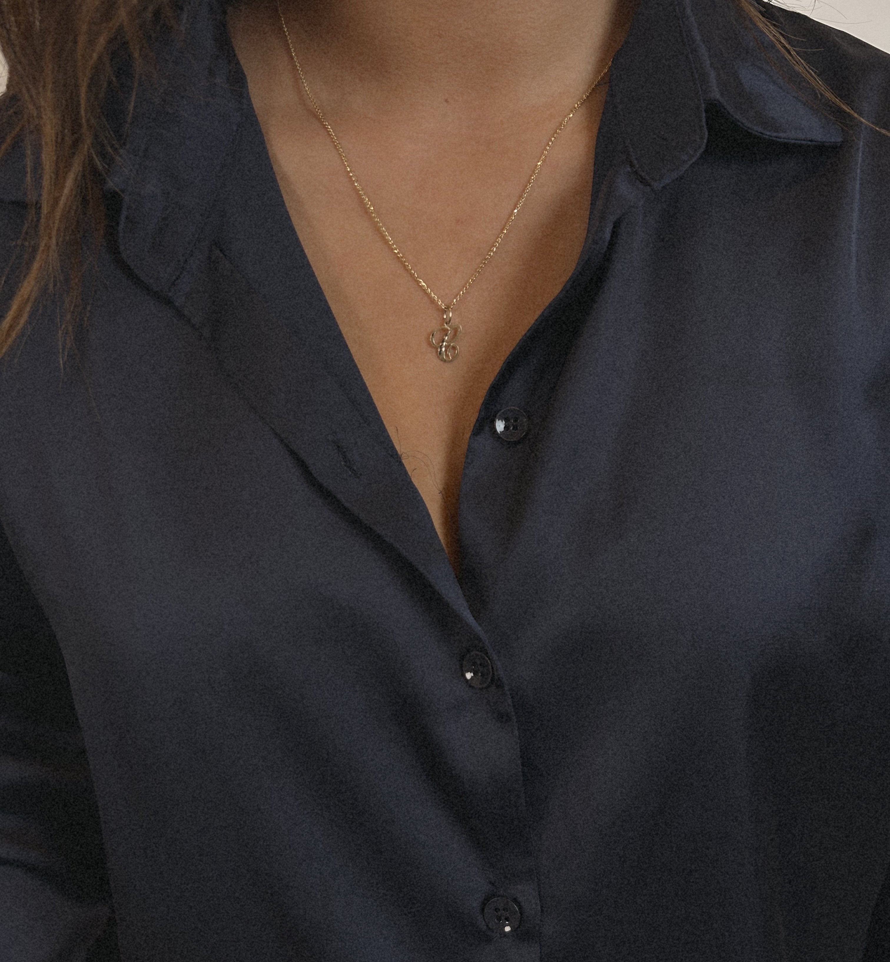 image of a model wearing a gold necklace with a letter c pendant