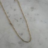 image of a gold figaro chain on a marble table