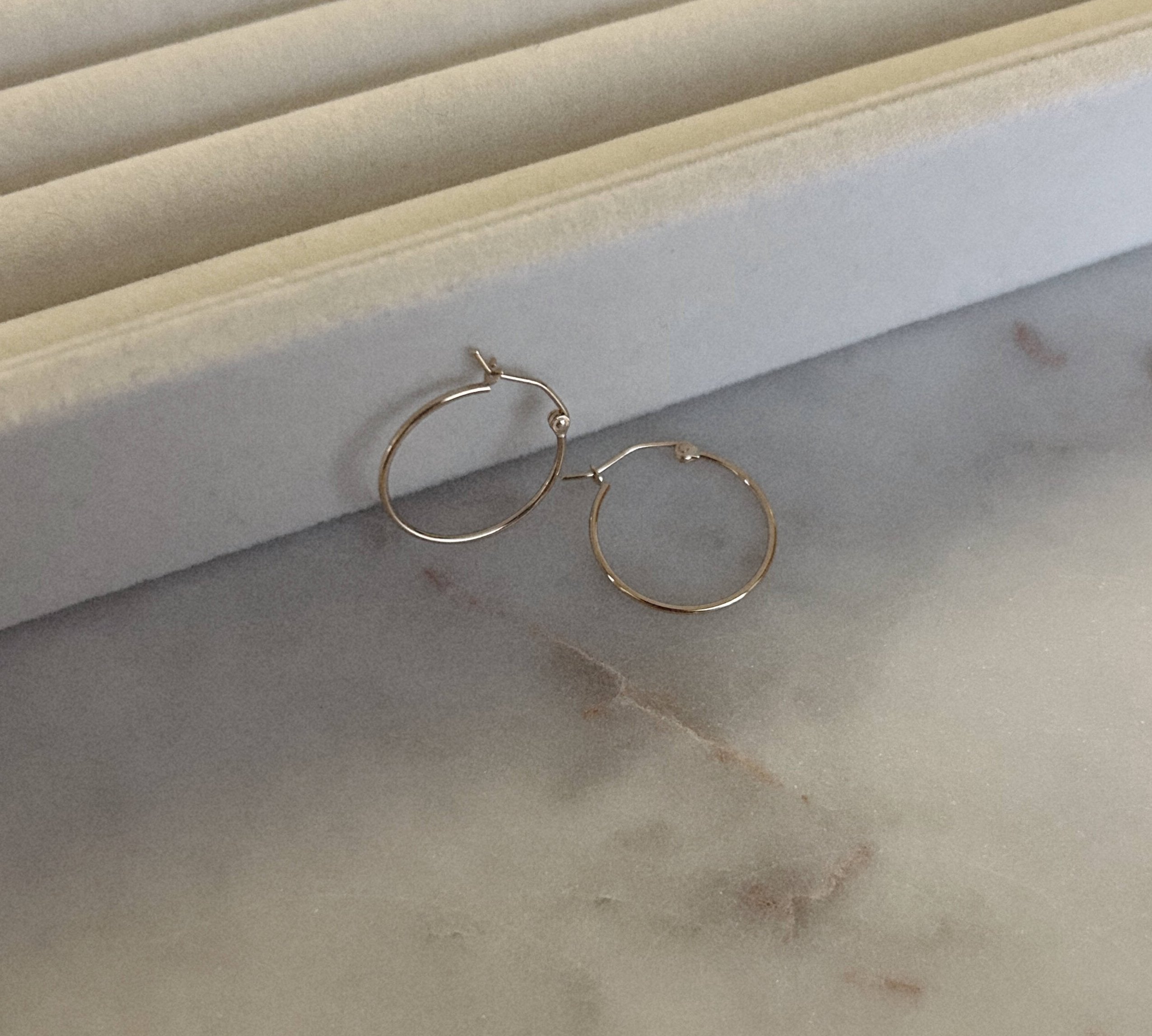 gold hoops against a ring holder tray on top of a marble table