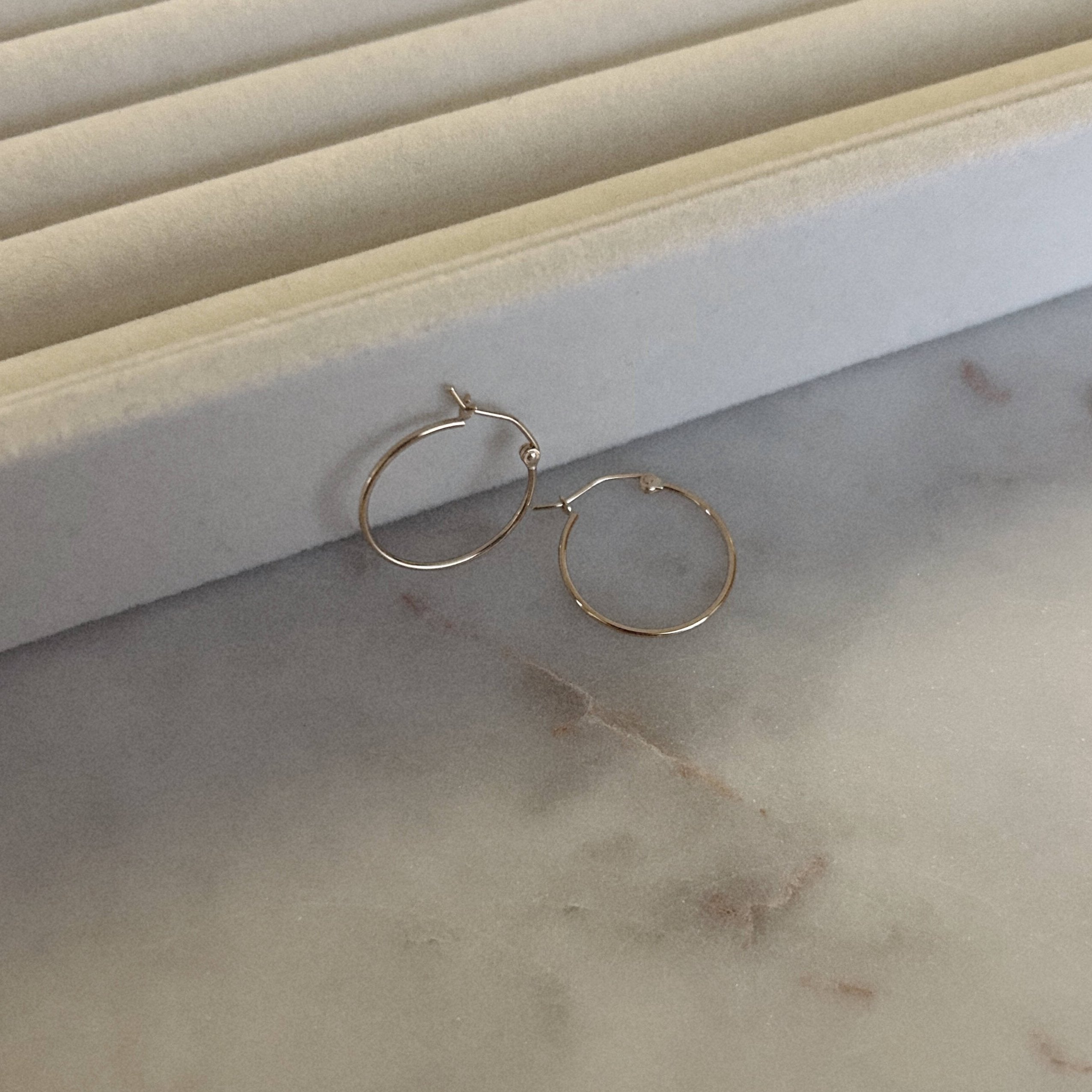 gold hoops against a ring holder tray on top of a marble table