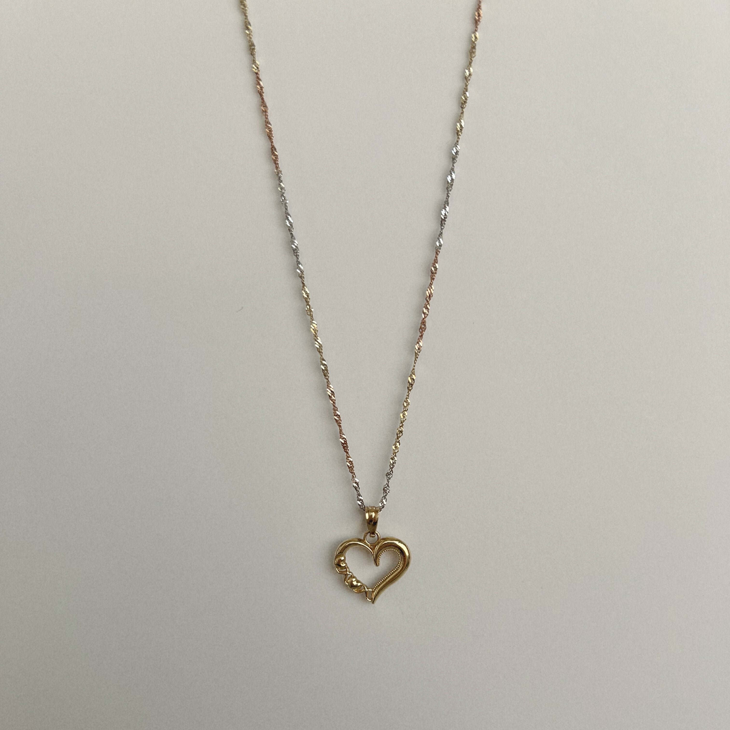 image of a heart gold pendant with a three color gold singapore chain with a white backdrop