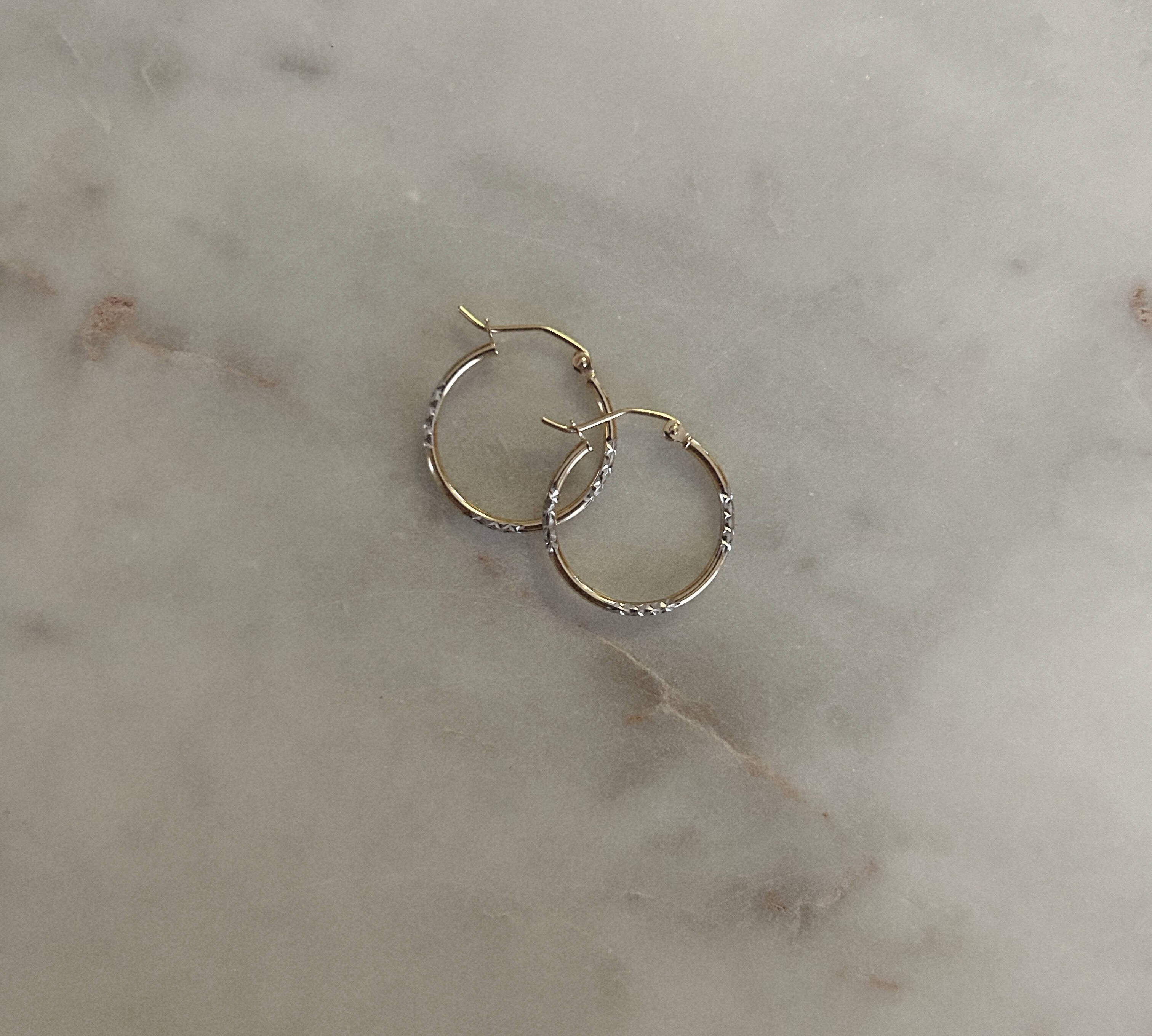 image of two tone earrings on top of a marble table