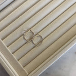 a two tone gold hoop earring on top a ring tray